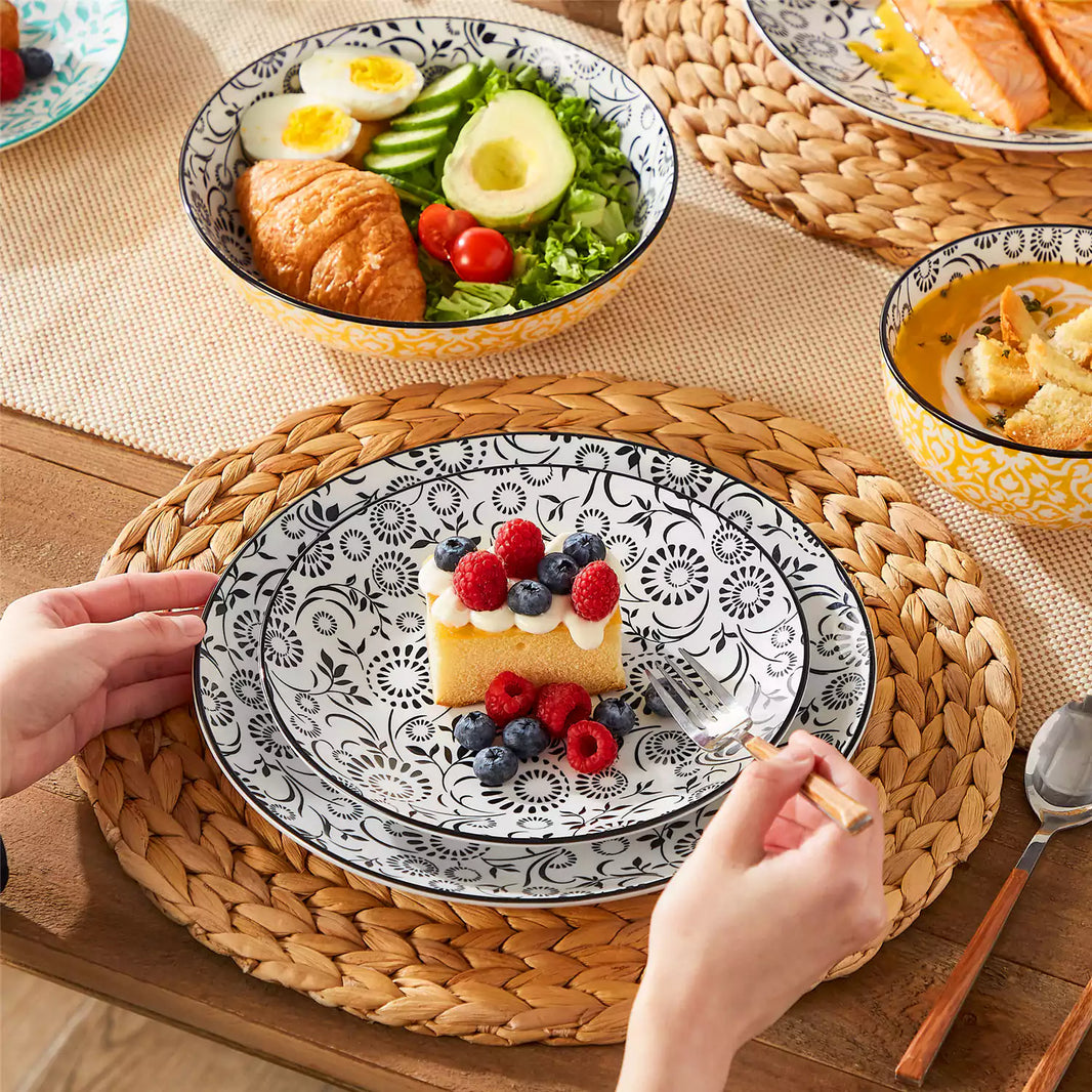 Selene porcelain dinnerware set on wooden table. Stacked plates with honey cake, avocado salad in pasta bowl, pumpkin soup in cereal bowl.