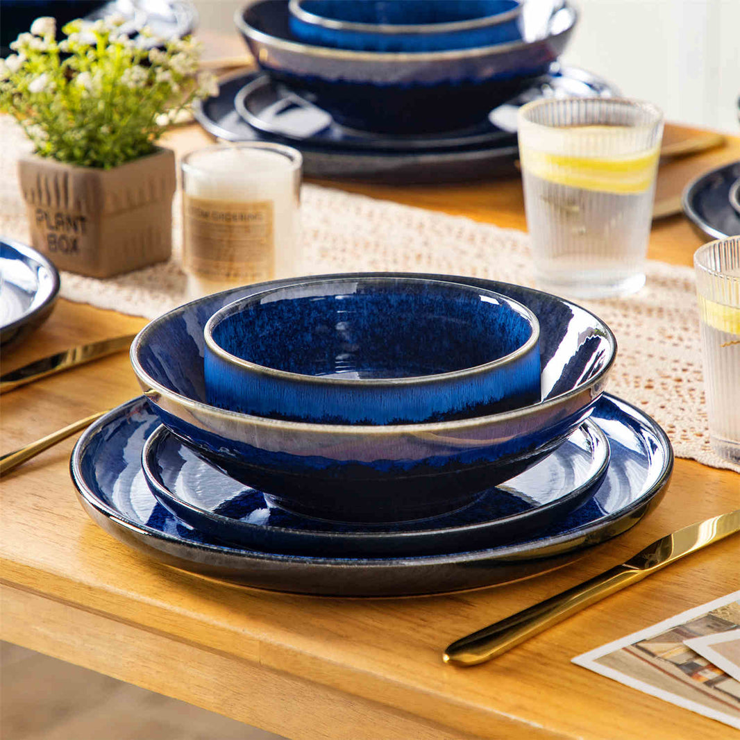 Solo dining set stacked on a wooden table, accented with a lace table runner, scented candles, and a refreshing glass of lemonade.